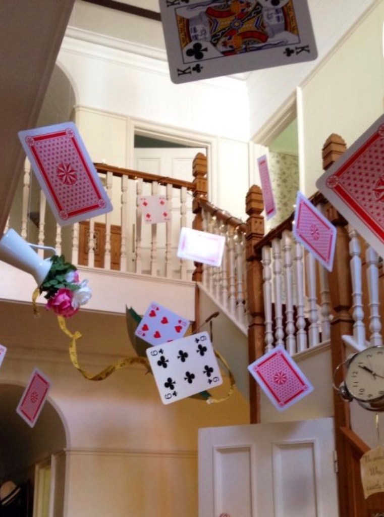 A staircase with playing cards floating in the air, featuring various designs and colors, and a decorative piece with flowers.